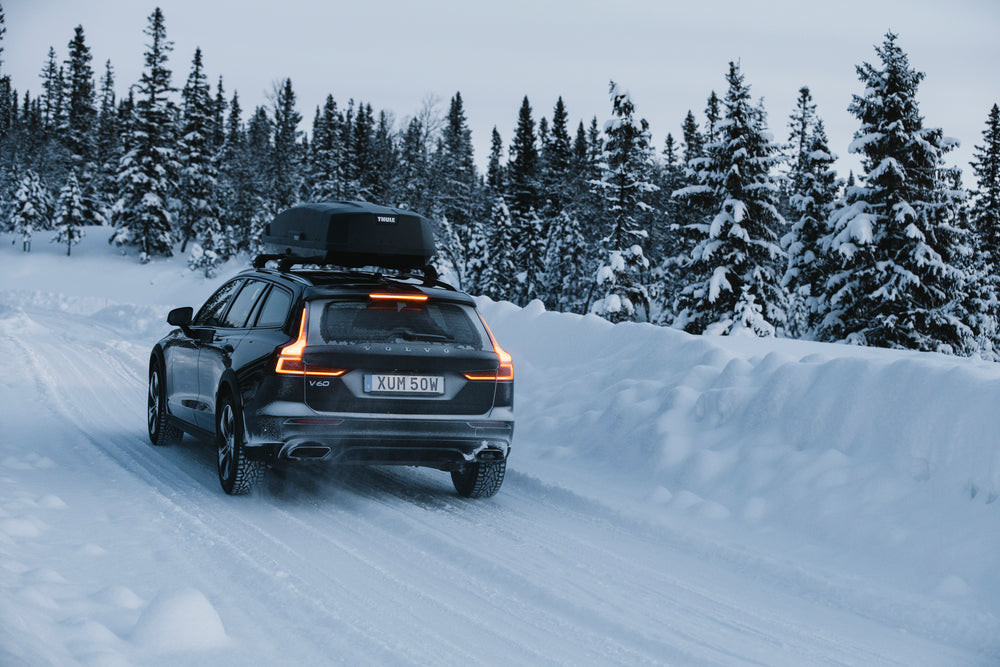 Car driving on a snowy road with snow-covered trees in the background